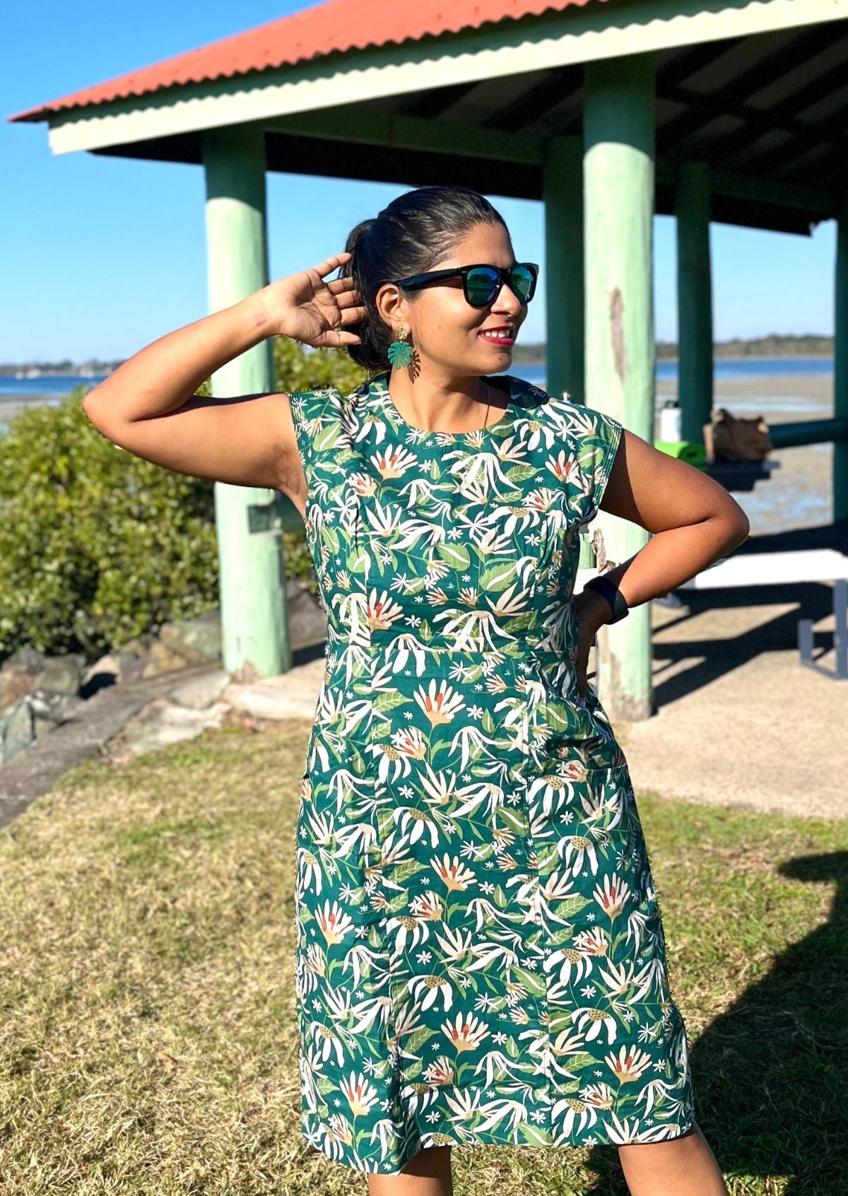 Woman wearing a cotton green dress with a floral pattern outdoors near a gazebo.