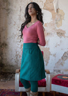 Model wears corduroy knee length teal skirt with a side zip and wide waistband