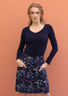 Model wears gorgeous floral print on navy blue based cotton corduroy skirt with both  hands in pockets.
