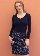 Woman wears printed A-line corduroy skirt with wide waistband, pockets and side zipper.