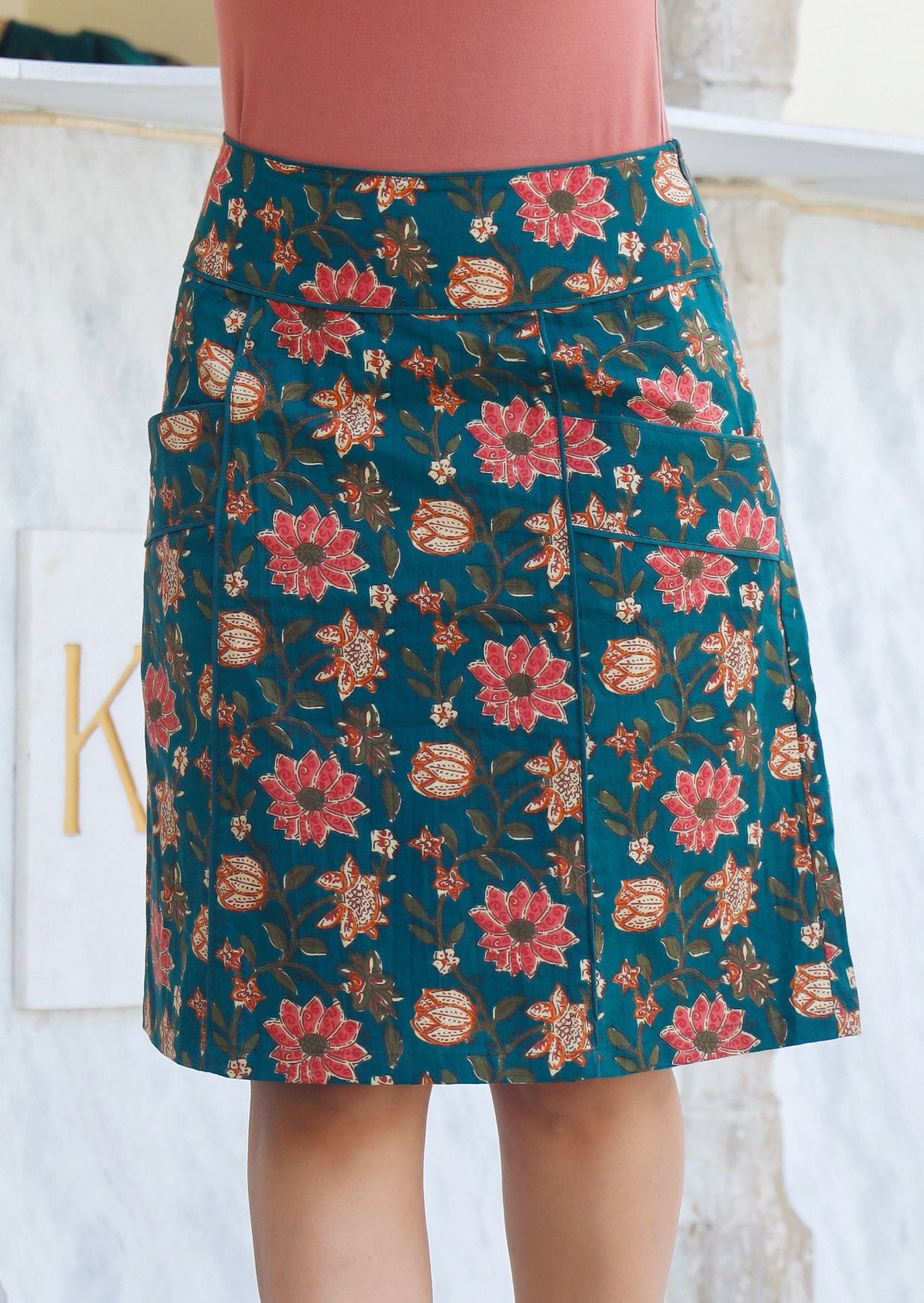 100% cotton green based floral print skirt with piped details around waistband and pockets.