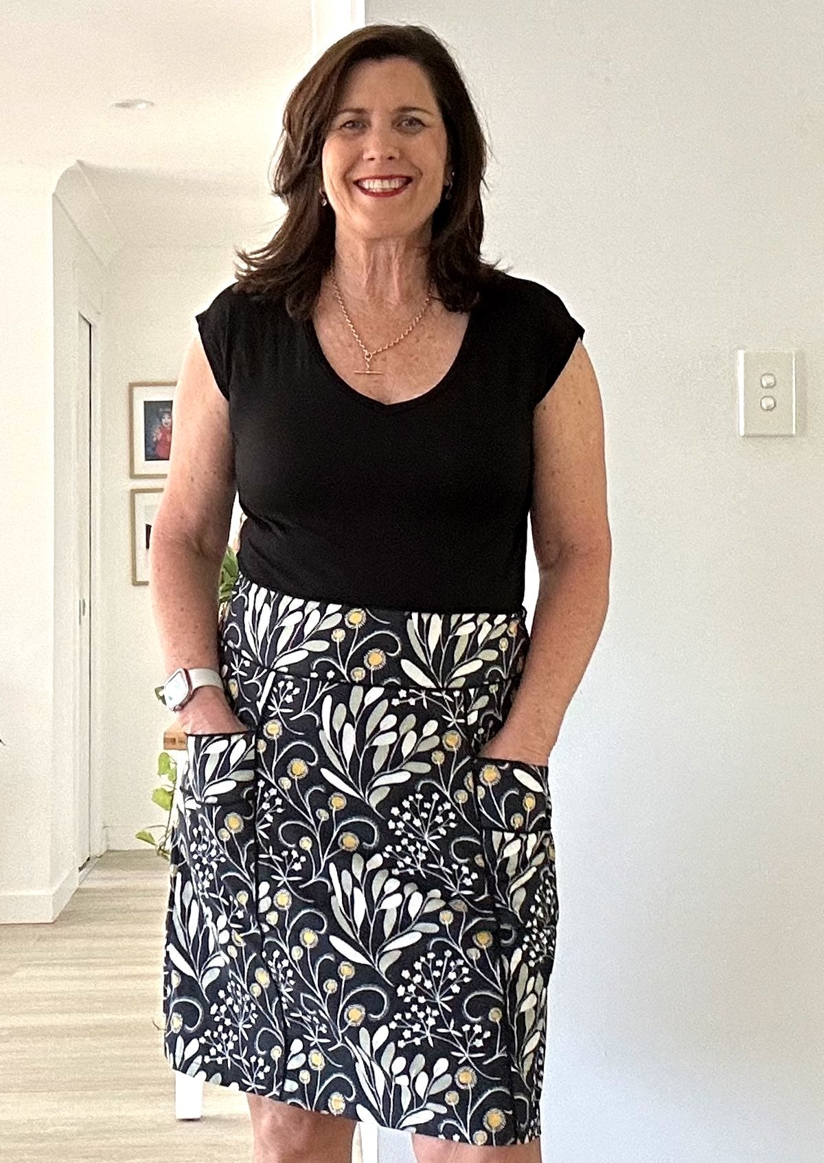 Woman wearing a black t-shirt and 100% cotton skirt with pockets indoors.