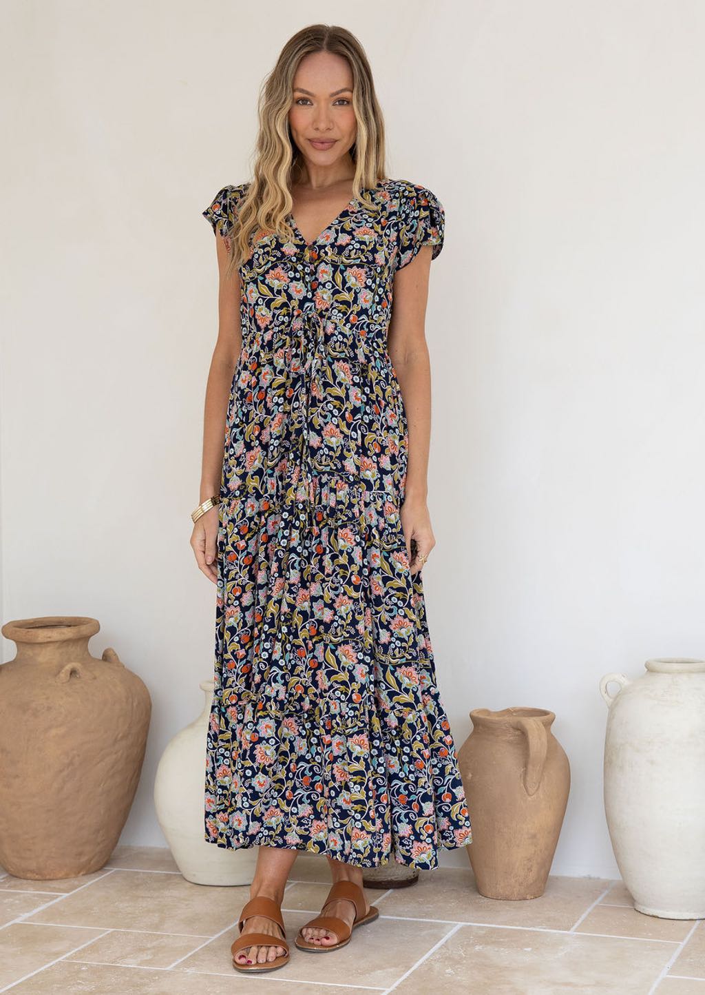 Woman wearing a floral dress standing in front of decorative vases.