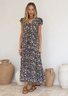 Woman wearing a floral dress standing in front of decorative vases.