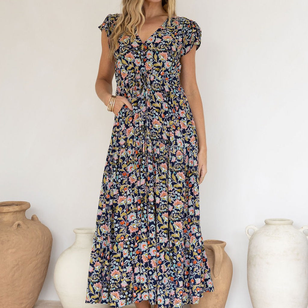 Woman wearing a floral Rayon dress standing in front of decorative vases.