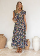 Woman wearing a floral Rayon dress standing in front of decorative vases.