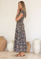 Woman wearing a floral Rayon dress standing in front of decorative vases.