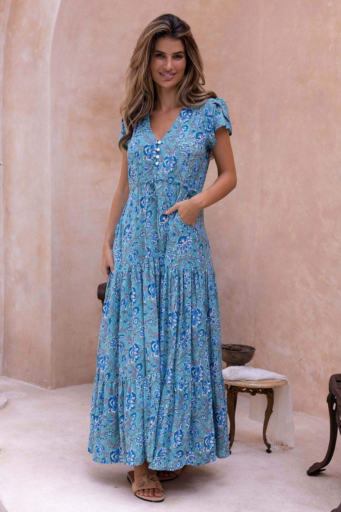 Woman wearing a blue floral sundress in an indoor setting