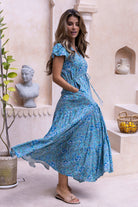 Woman wearing a aqua floral sundress in with hands in pockets