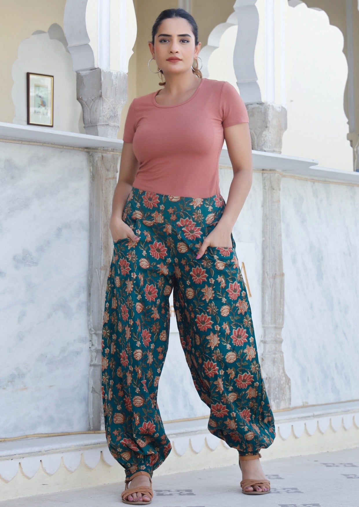 Model wears 100% cotton harem pants in gorgeous green based floral print with buttoned ankles and hands in pockets.