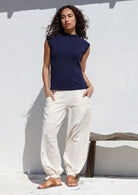 Woman posing with both the hands in pants pocket wearing a 100% cotton wide leg pants with cuffed ankles and shirred back waist.c