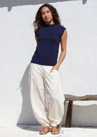 Woman wearing a navy blue basic top and white pull-on cotton pants with cuffed ankles, wide leg fit and pockets.