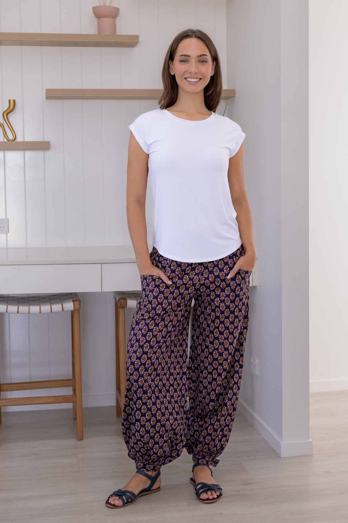 Woman wears cotton harem pants with buttoned ankle and pockets, paired with a basic white top