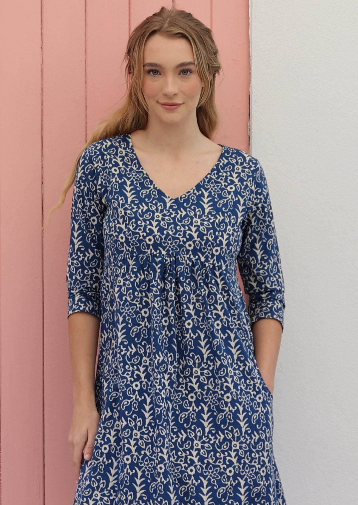 Close up of woman in cotton V-neckline dress with 3/4 sleeves, in an Indian floral print on a blue base