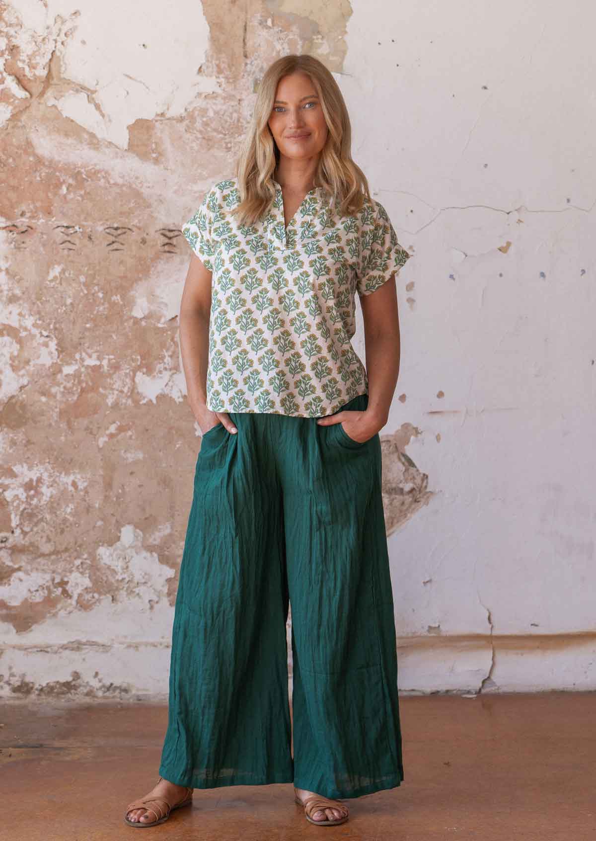 Model poses in cotton collared short sleeve top with yellow and green floral print on a white base