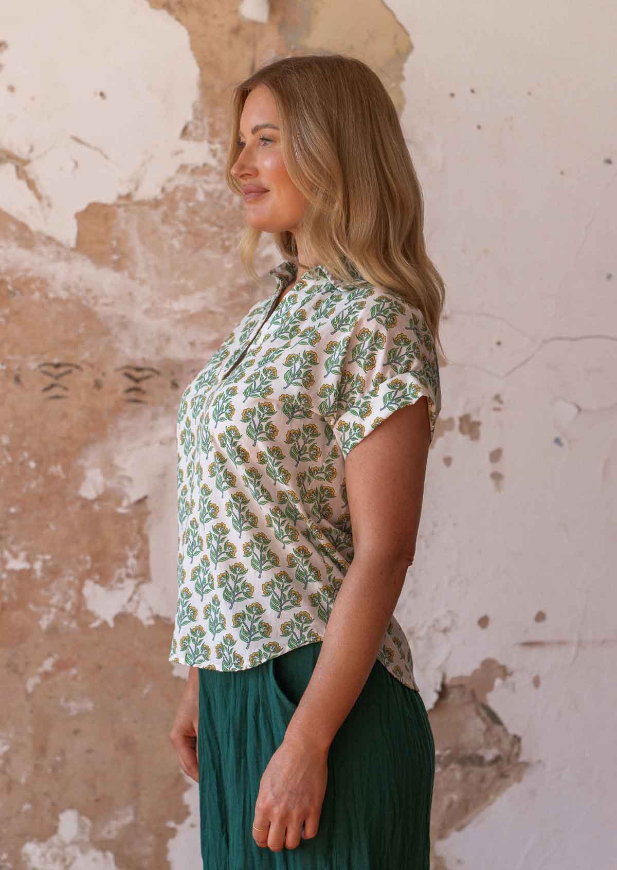 Model stands sideways in 100% Cotton  top with rolled cuffs on short sleeves and collar