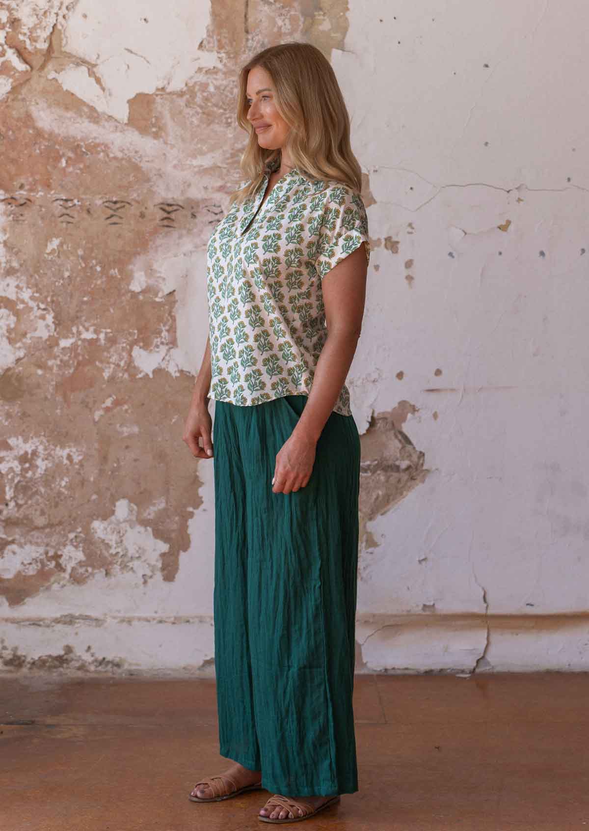 Woman wears cotton short sleeve top in yellow and green floral print on a white base