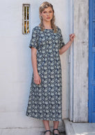 Woman is wearing a blue floral dress with pockets.