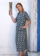 Woman is wearing a dress with a round neckline and a keyhole button back closure.