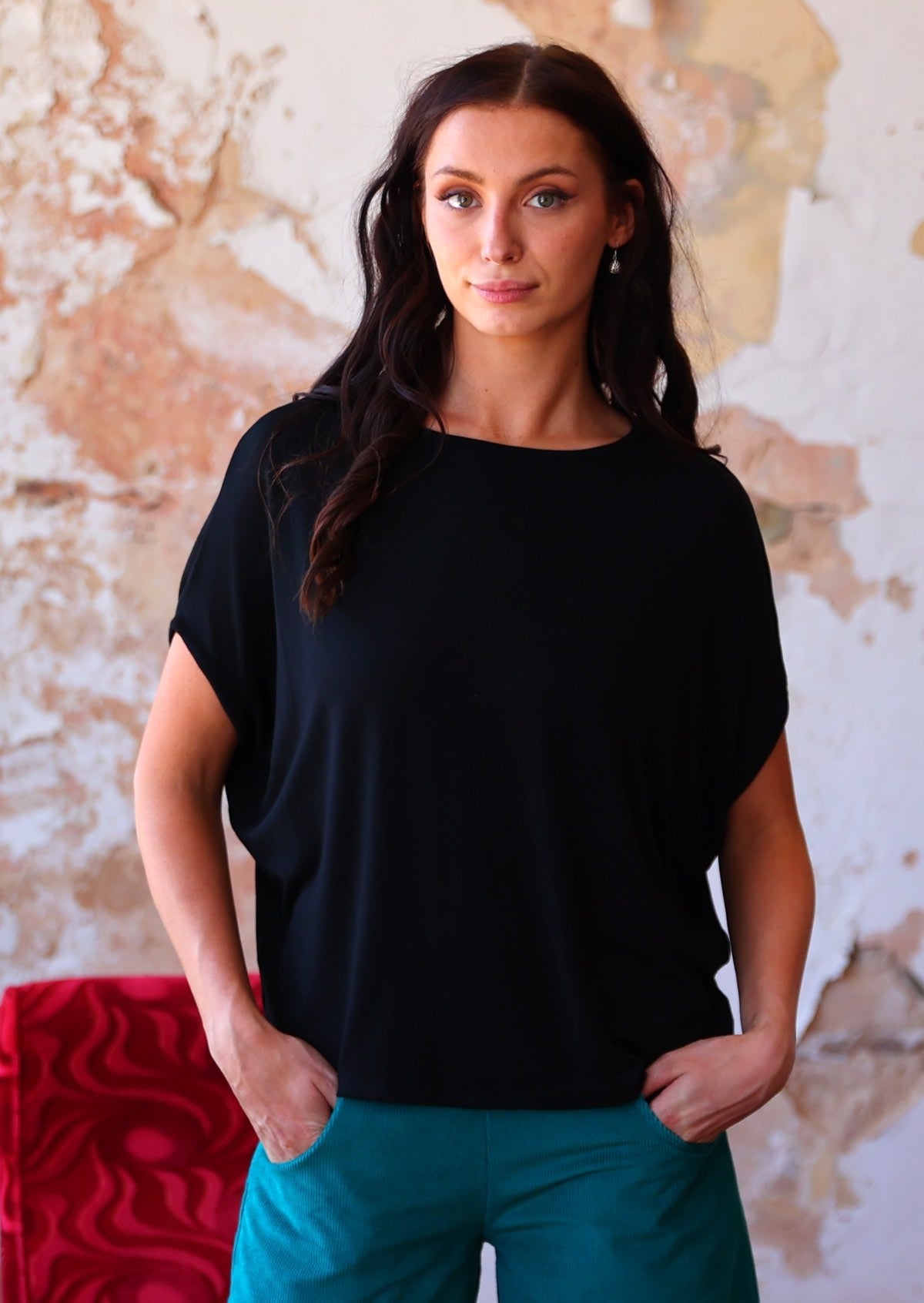 Woman wearing batwing t-shirt black over teal corduroy pants