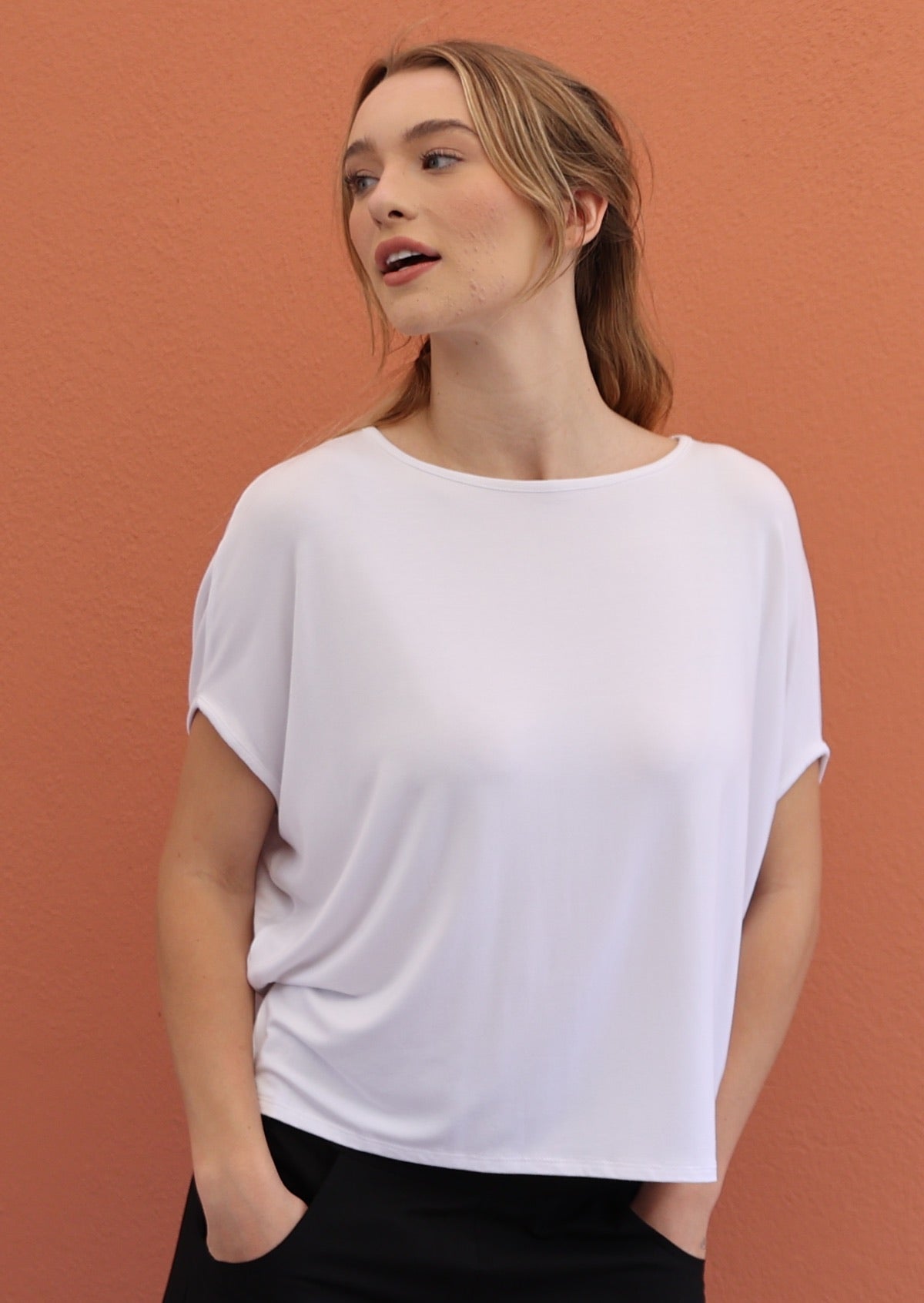 Woman wears white stretch rayon batwing t-shirt paired with black pants