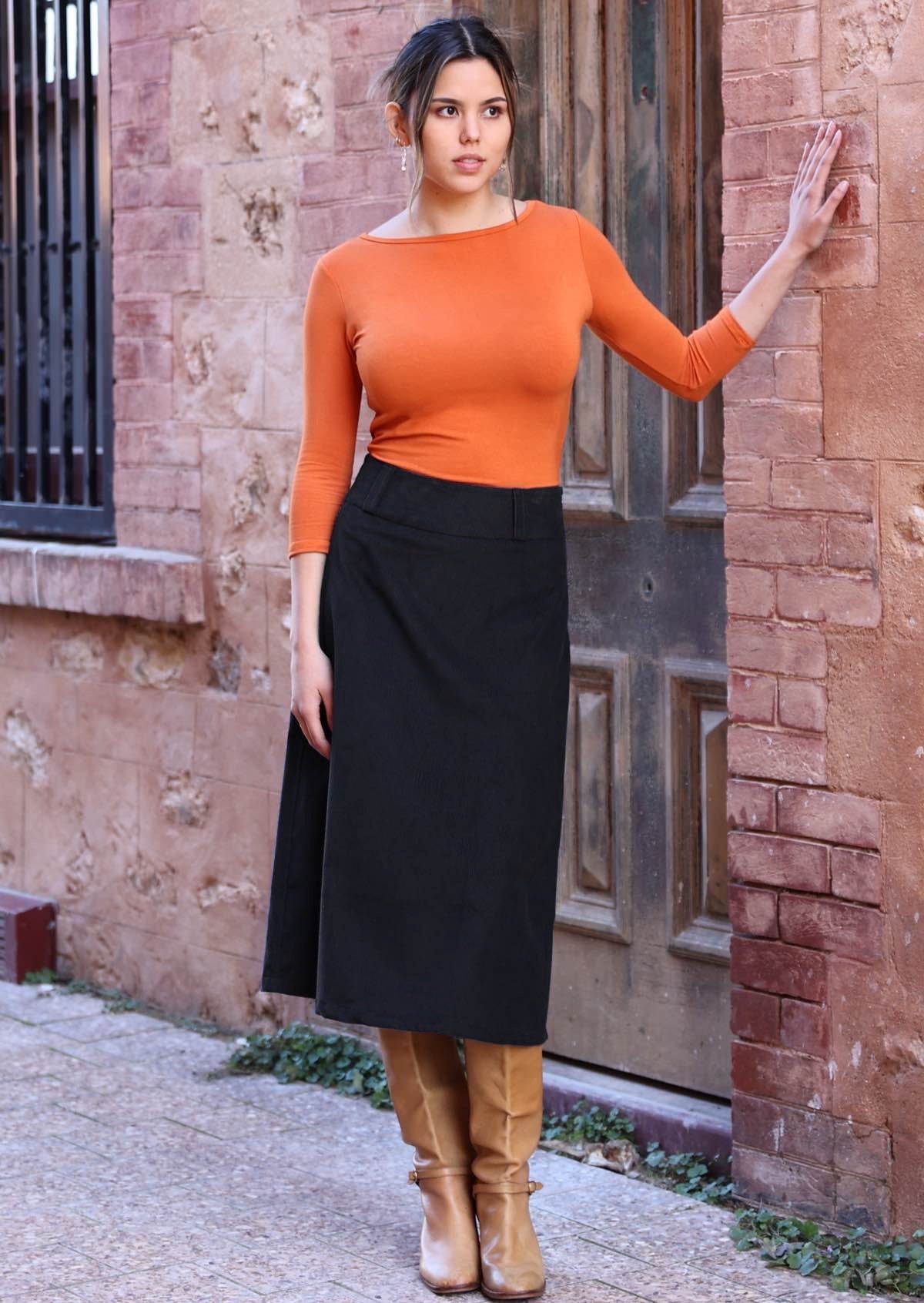 Woman wearing a-line below knee length black corduroy skirt