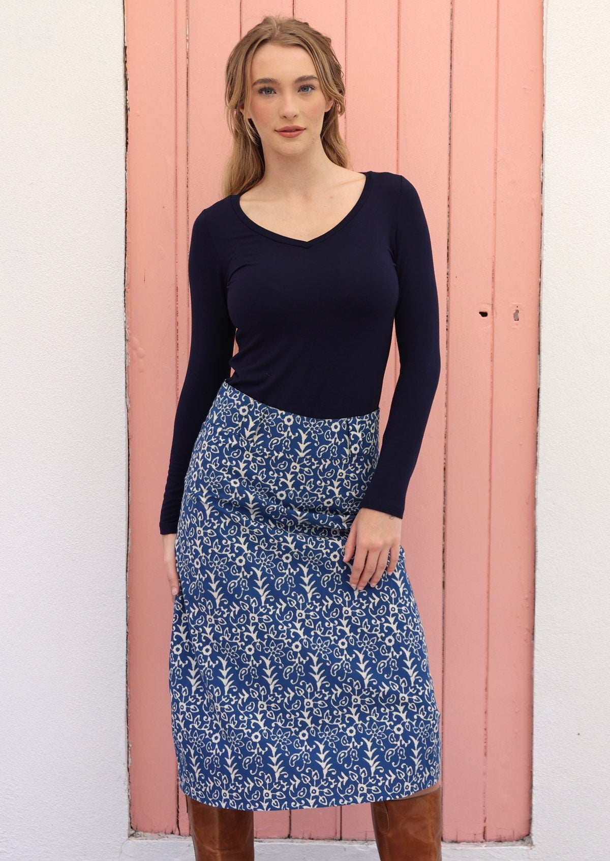 Woman wears cotton midi length A-line skirt with belt loops paired with a long sleeve stretch rayon top in navy blue