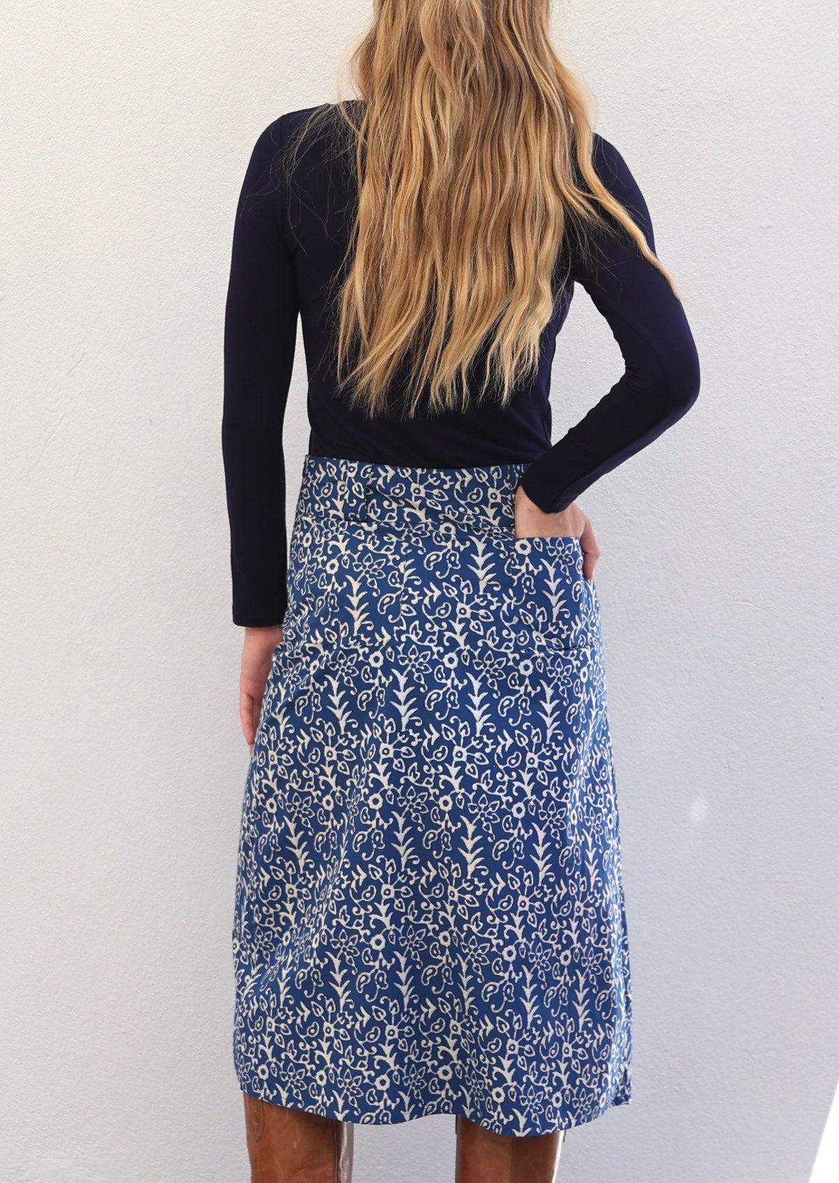 Woman faces away from camera in cotton A-line midi length skirt with her hand in back pocket