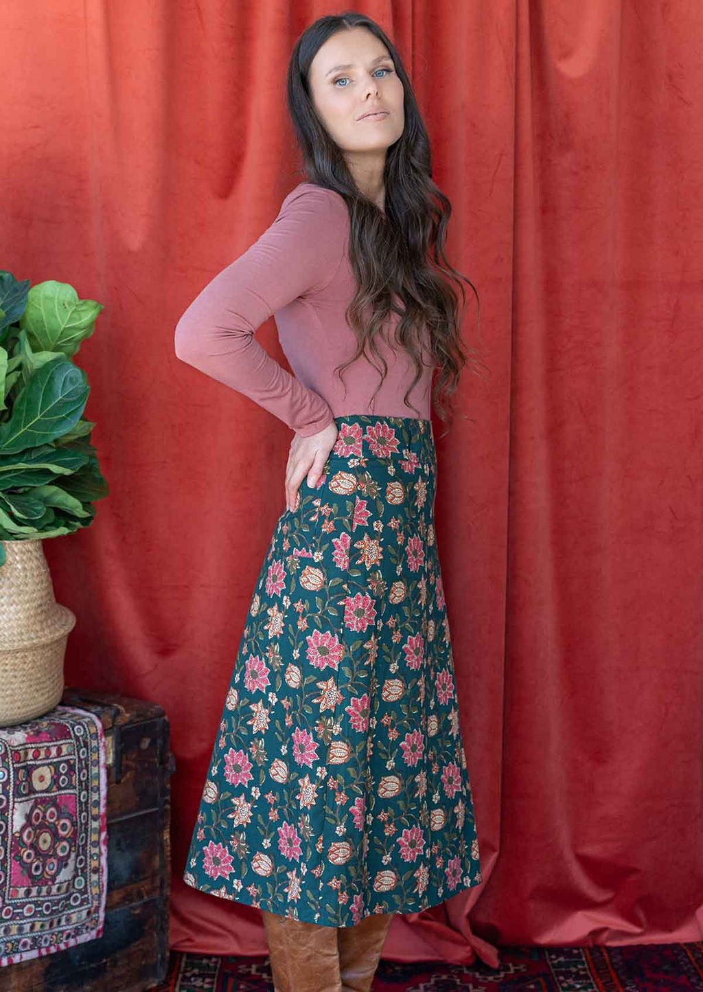 Woman stands sideways in cotton A-line skirt with belt loops and side zip, and back pocket.