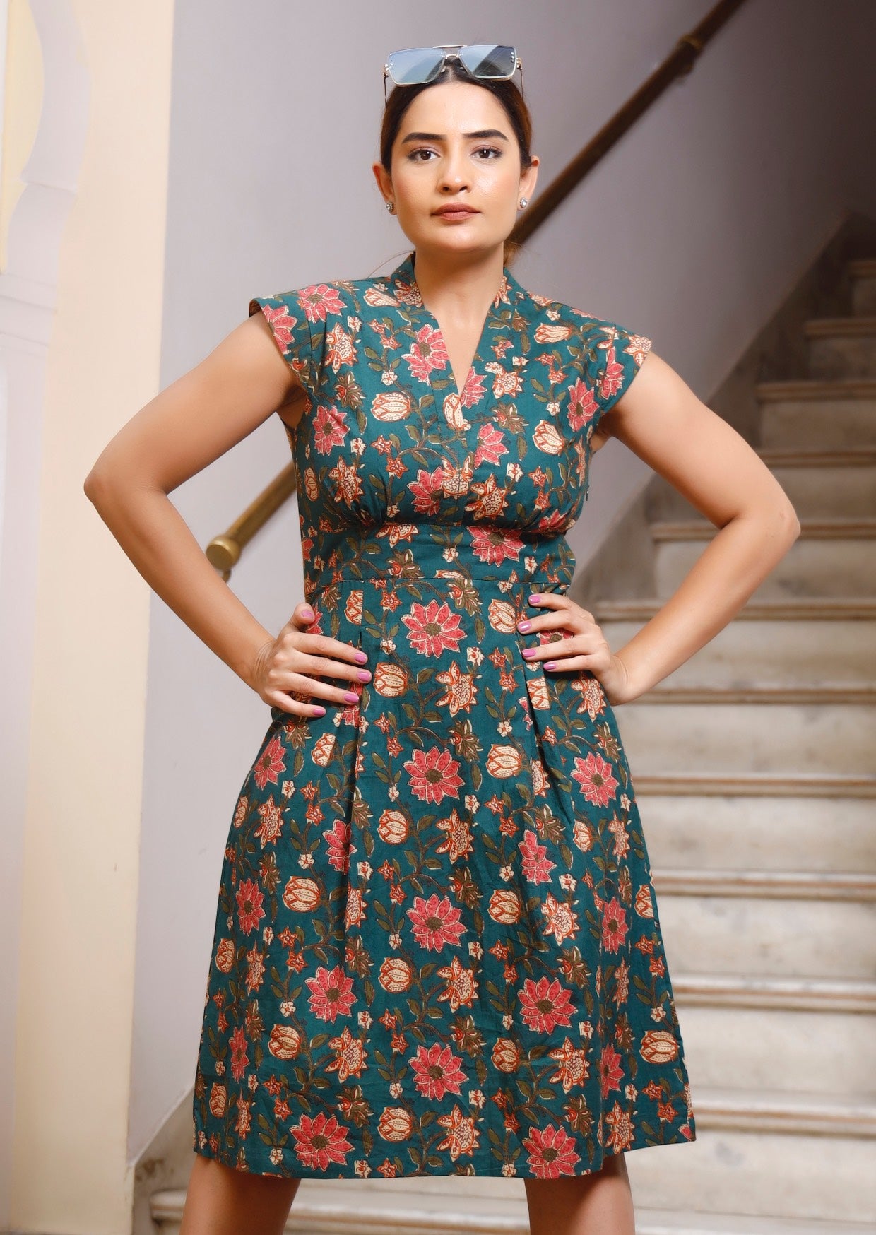 Model with both the hands on hip wears 100% cotton dark green based floral printed retro style dress.