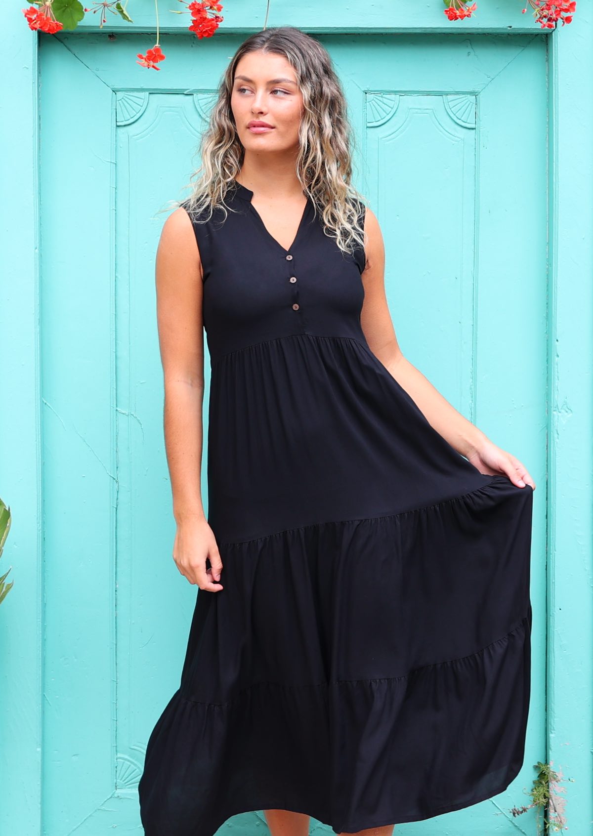 Woman in long black casual dress in front of aqua door