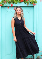 Woman wearing long black casual dress in front of aqua door