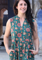 Closeup of woman wearing a green cotton dress with buttoned bodice , mandarin collar and hands in pockets.