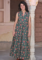 Model standing in sleeveless maxi dress with buttoned bodice and mandarin collar forming V neck.