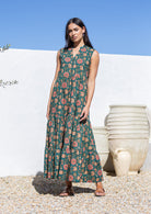 Woman wearing a Indian Cotton floral dress standing outdoors with a white wall and blue sky in the background.