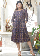 Model wearing relaxed fit cotton dress sitting just below the knee length with wide round neckline and hands in pocket.