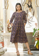 Model with dark hair wears 100% cotton relaxed fit dress in purple based pink ,cream and light brown floral print.