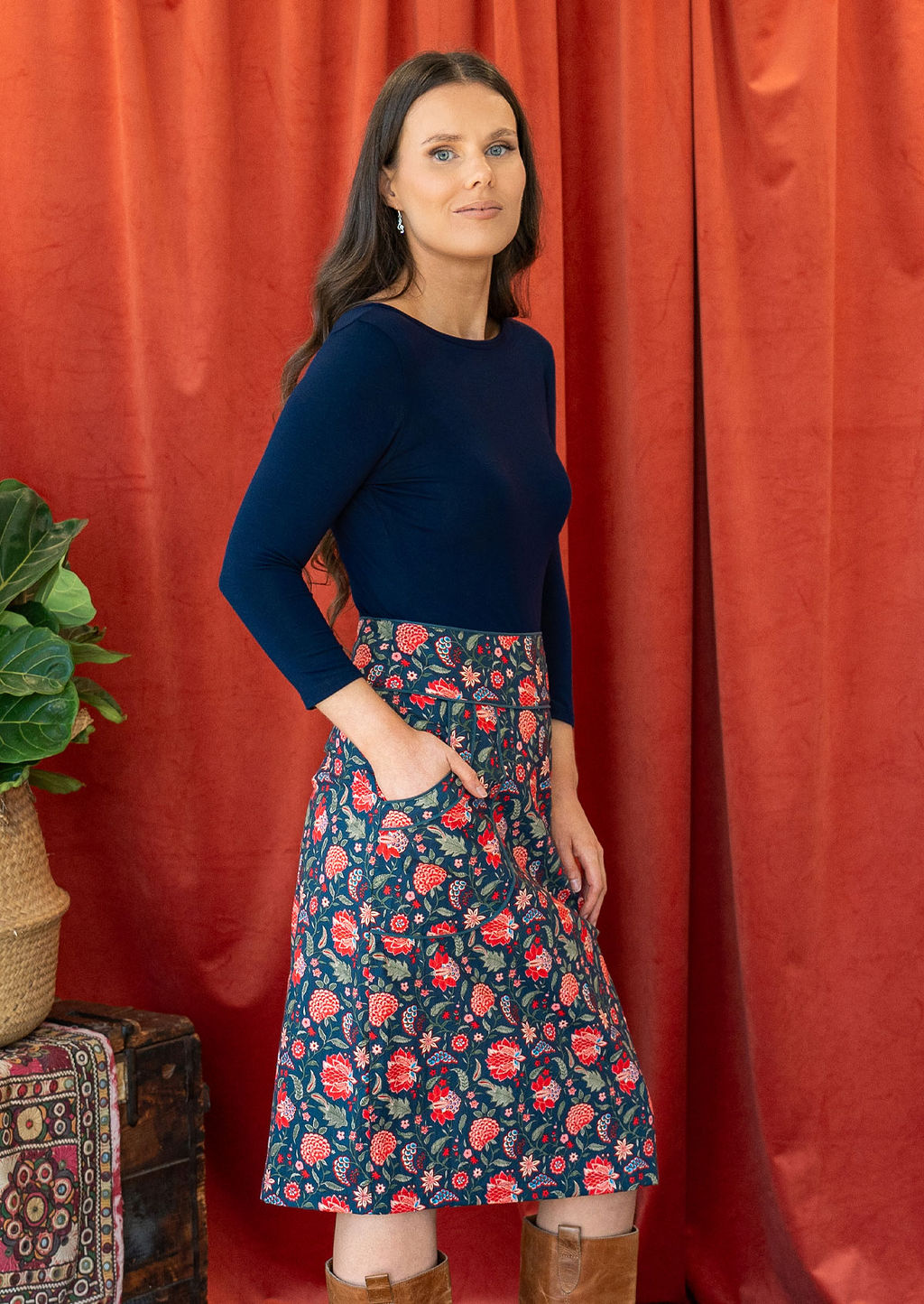 Model poses in cotton floral print knee length pencil skirt with hand in pockets, paired with a dark blue stretch rayon top