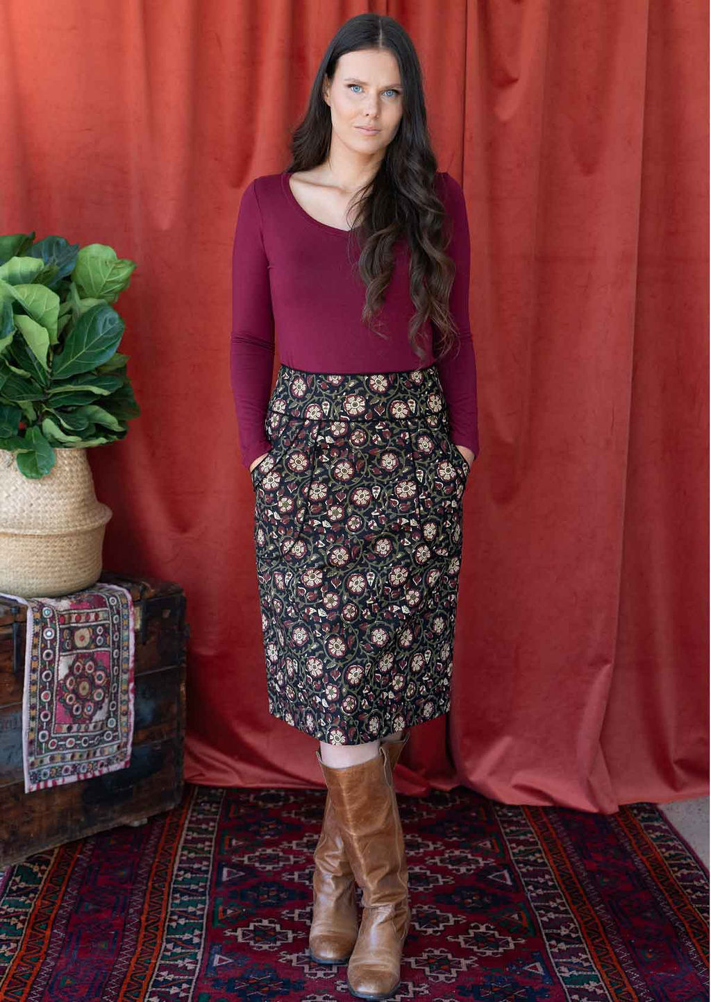 Woman wears black based floral print cotton pencil skirt with high waistband, with hands in deep pockets