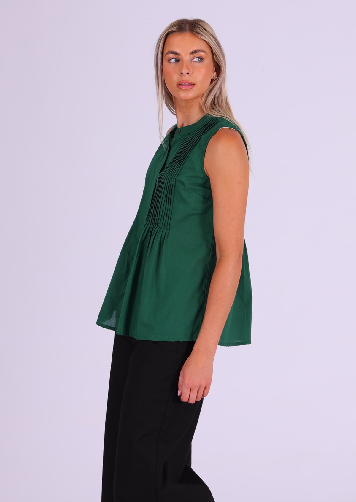 Model wears deep green sleeveless cotton top that covers the hips, with tiny pleats across bust that make the lower half a relaxed fit