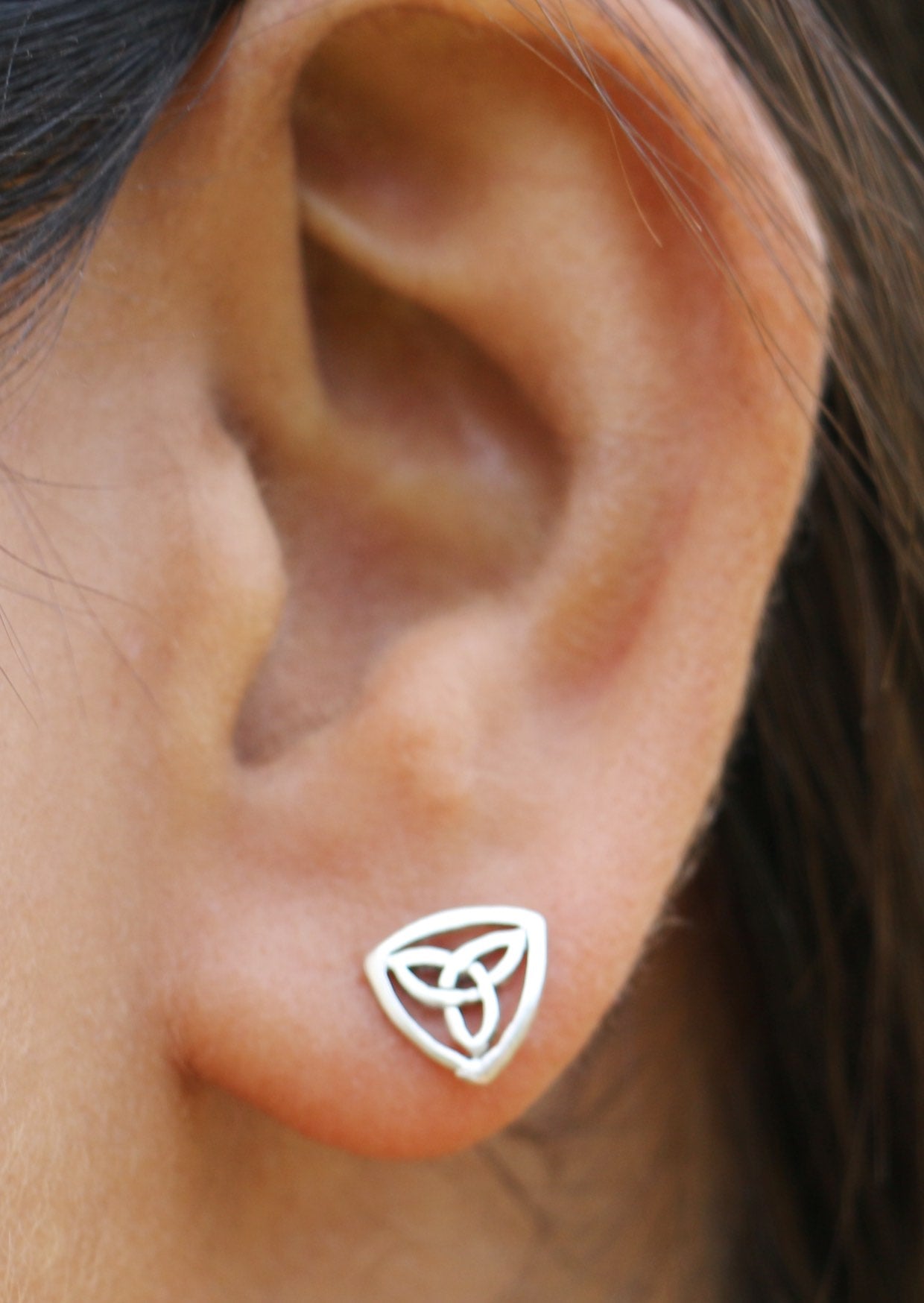 Close-up of an ear wearing a silver Celtic Triangle Studs featuring an intricate trinity knot design butterfly backs