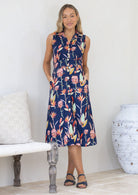 Woman wearing a sleeveless floral button through shin length dress in a minimal setting