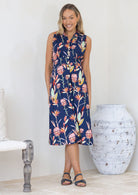 Woman wearing a midi length floral cotton sleeveless sun dress with a collar and buttons