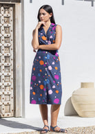 Woman posing in button through, sleeveless cotton dress with collar and pockets.