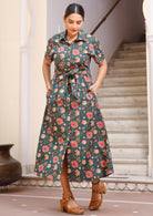 Model wears 100% cotton shirt sleeve dress in pinkish bold floral print with pockets and thick waist tie.