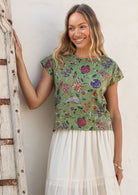 Woman wearing a moss green floral round neck cotton top against a white background.
