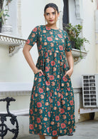 Model wears 100% cotton midi length short sleeve dress in vibrant pinkish floral print on deep green base.