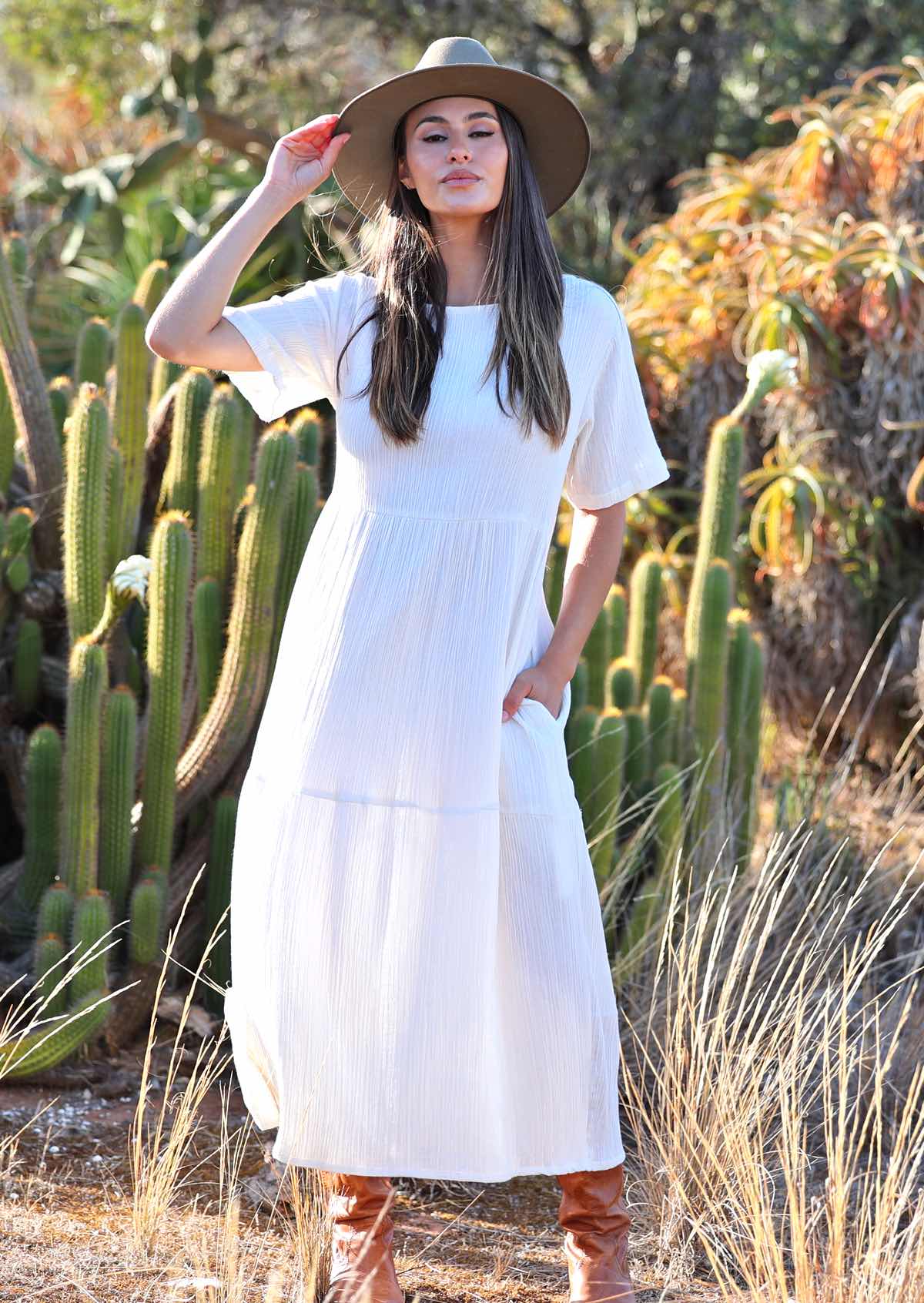 Woman with dark hair in beautiful
white cotton maxi dress with hands in pockets