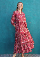 Woman wears cotton tiered maxi dress with a buttoned bodice with a V-neckline and mandarin collar, and 3/4 sleeves, with hand in pocket