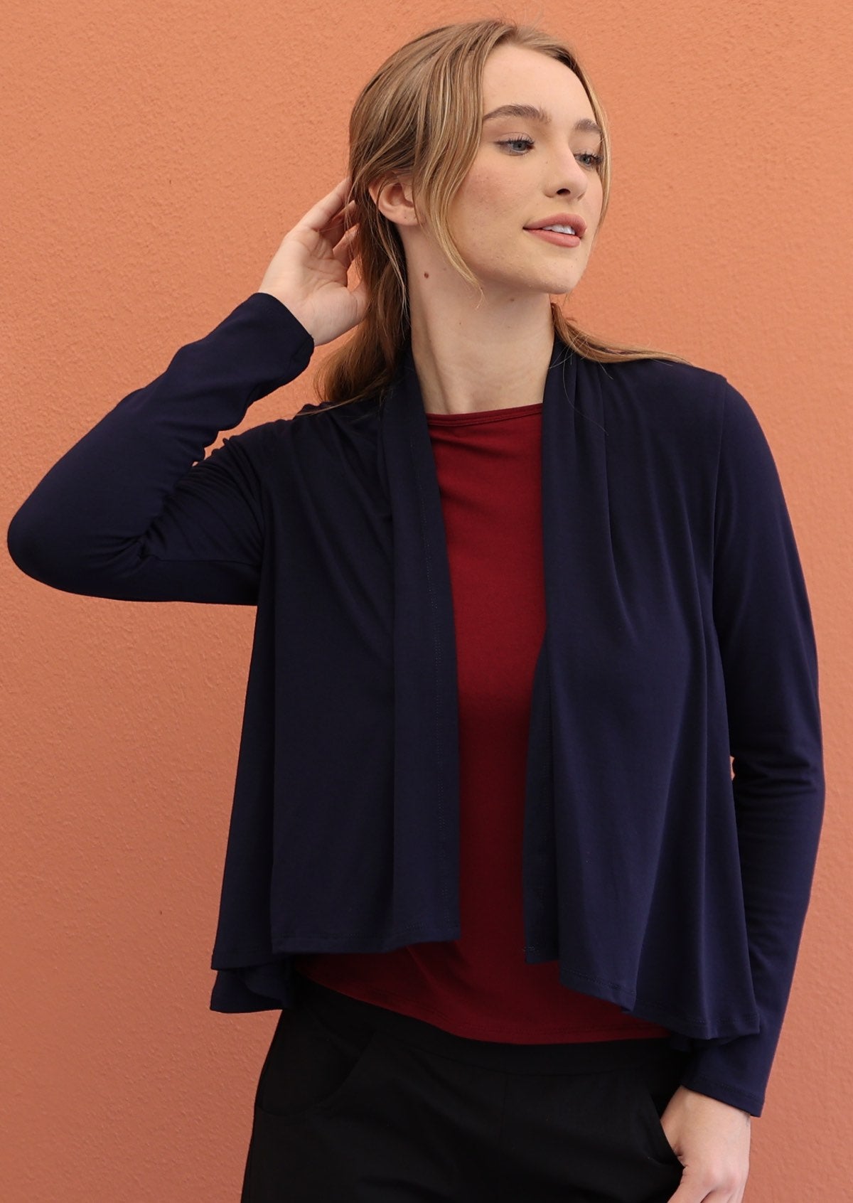 Model wears navy blue long sleeve stretch rayon cardi with maroon top and black pants underneath